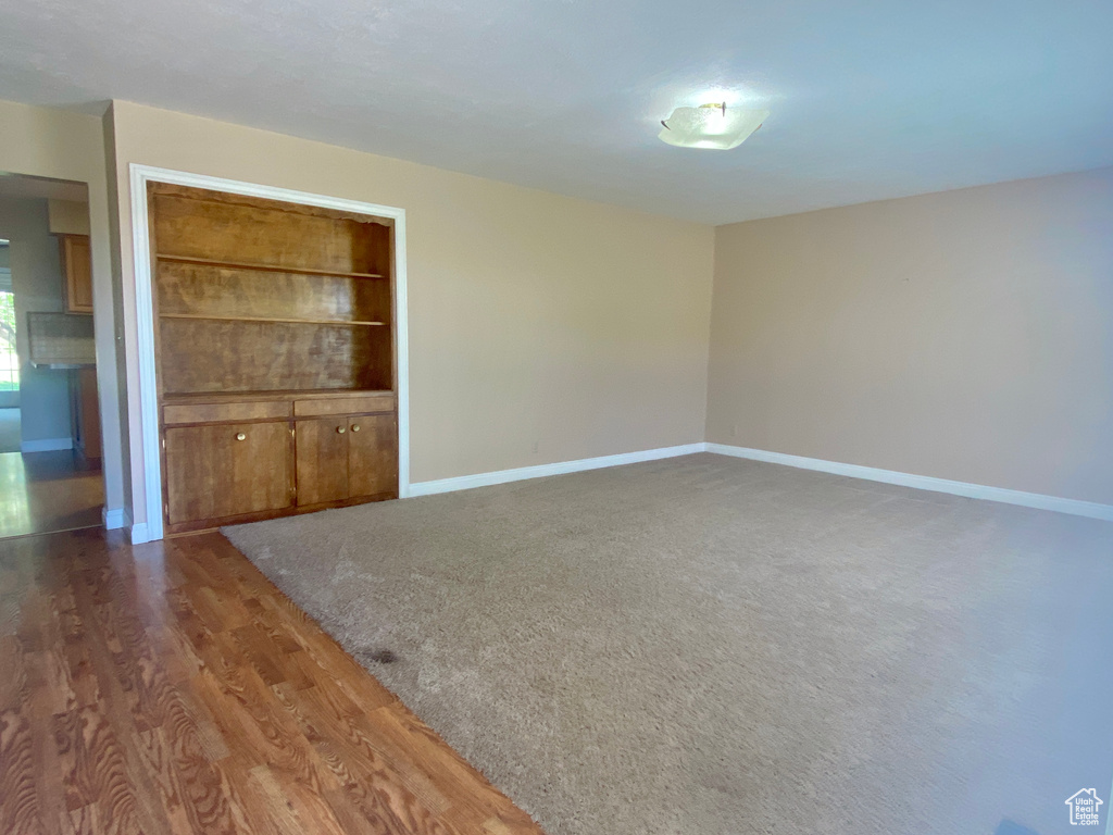 Spare room featuring baseboards and dark wood-style flooring
