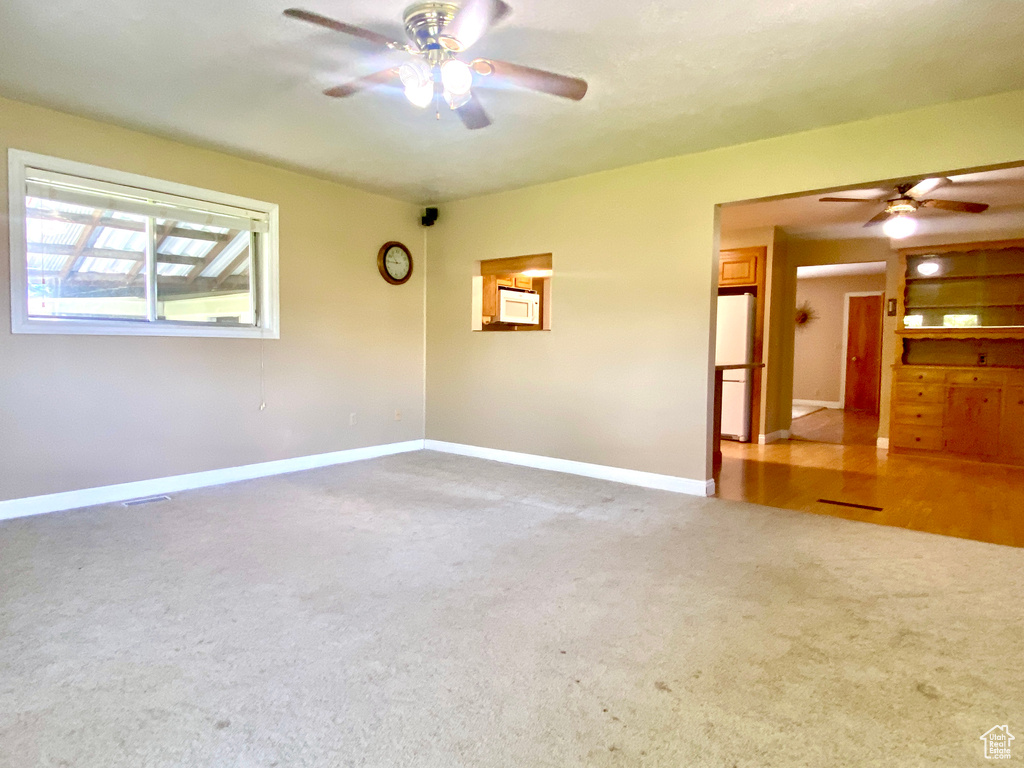 Carpeted spare room with ceiling fan and baseboards