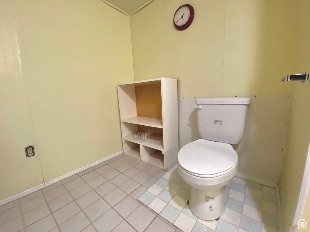 Bathroom featuring toilet, tile patterned floors, and baseboards
