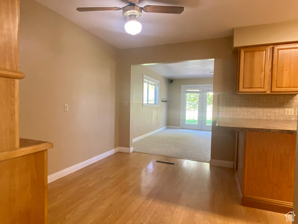 Kitchen featuring ceiling fan, light wood-style flooring, baseboards, brown cabinetry, and backsplash