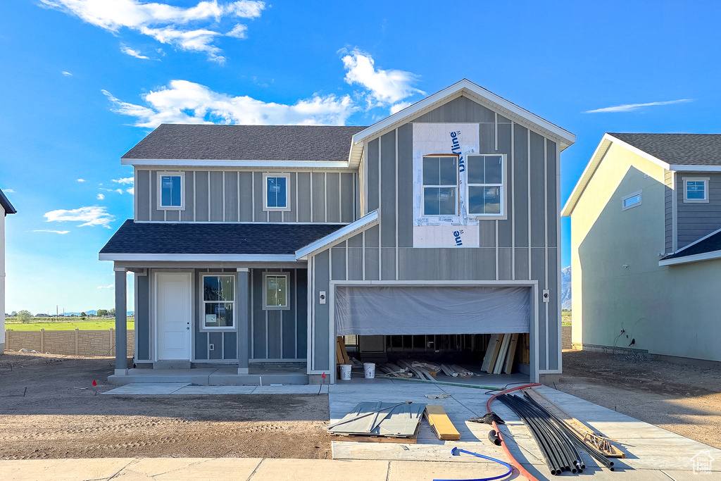 View of front facade featuring board and batten siding, concrete driveway, a shingled roof, a garage, and a porch