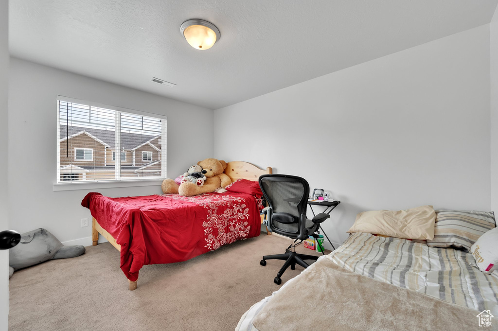 Carpeted bedroom featuring baseboards and visible vents