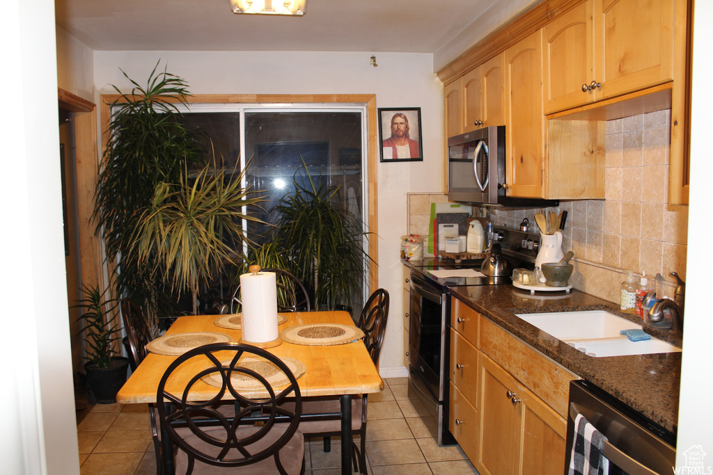Kitchen featuring range with electric cooktop, stainless steel microwave, light tile patterned floors, tasteful backsplash, and wine cooler
