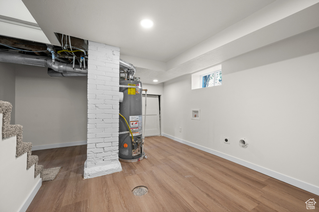 Below grade area with water heater, wood finished floors, baseboards, recessed lighting, and stairs
