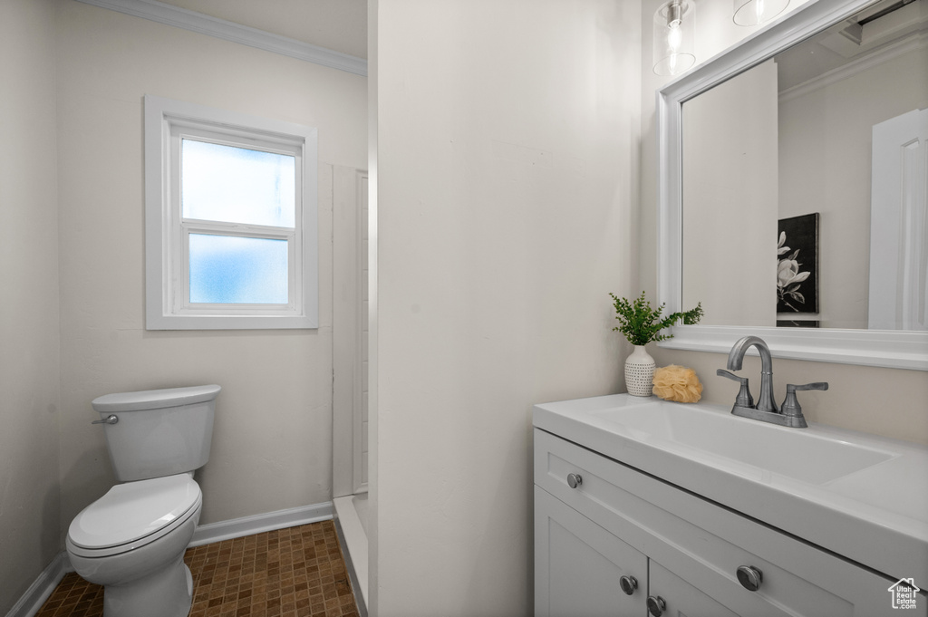 Bathroom featuring baseboards, vanity, toilet, and crown molding