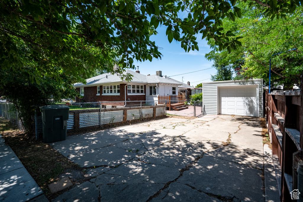 Ranch-style home with a fenced front yard, an outdoor structure, concrete driveway, and brick siding