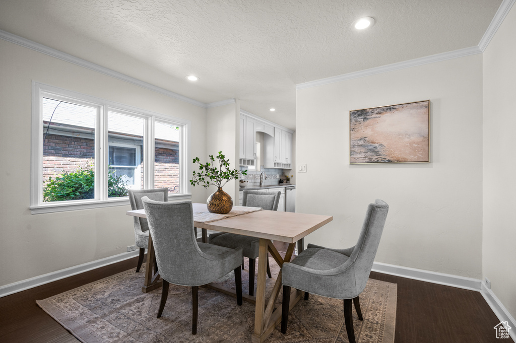 Dining area with crown molding, dark wood-style flooring, baseboards, a textured ceiling, and recessed lighting