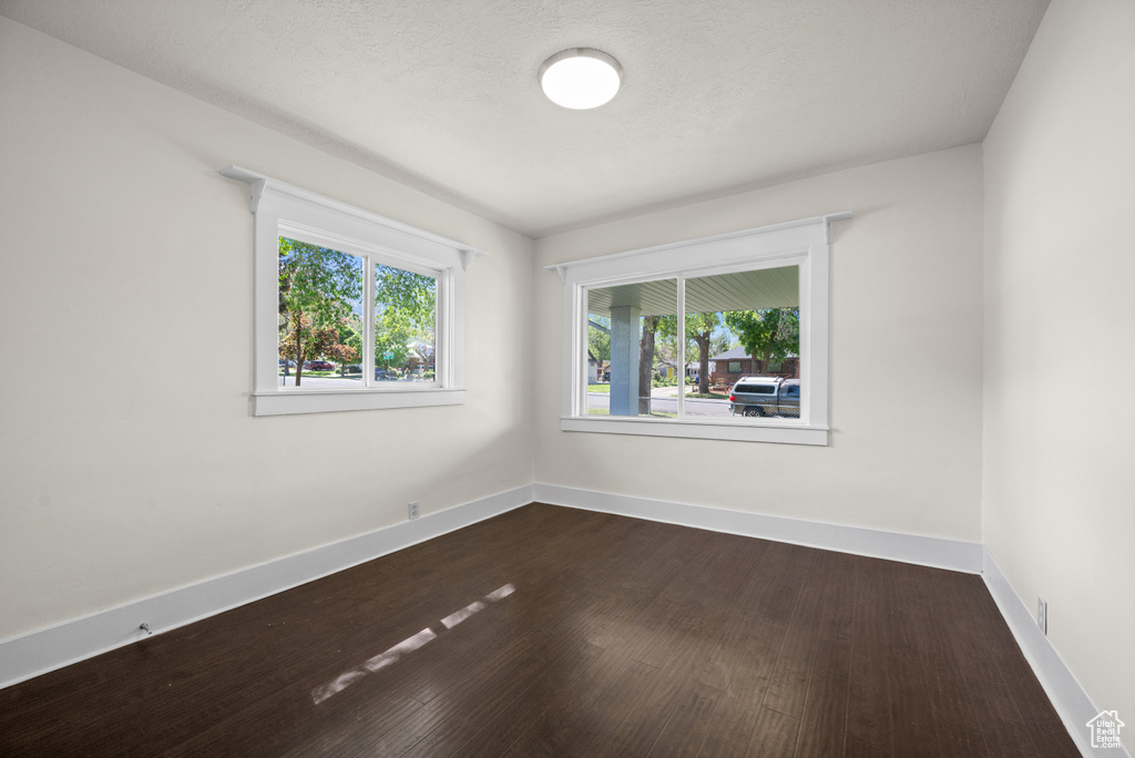 Unfurnished room featuring baseboards and dark wood-type flooring