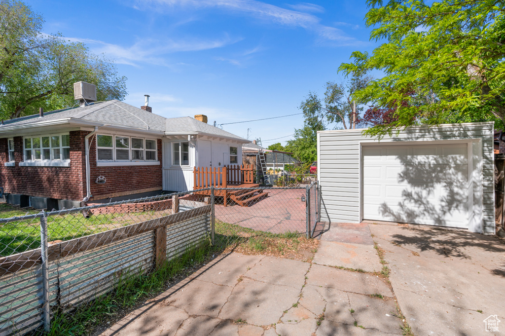 View of front facade featuring central AC, fence, an outdoor structure, and driveway