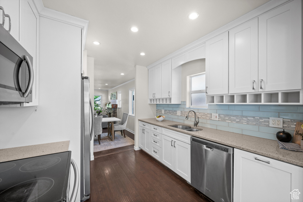 Kitchen featuring stainless steel appliances, a sink, dark wood-style floors, decorative backsplash, and white cabinetry