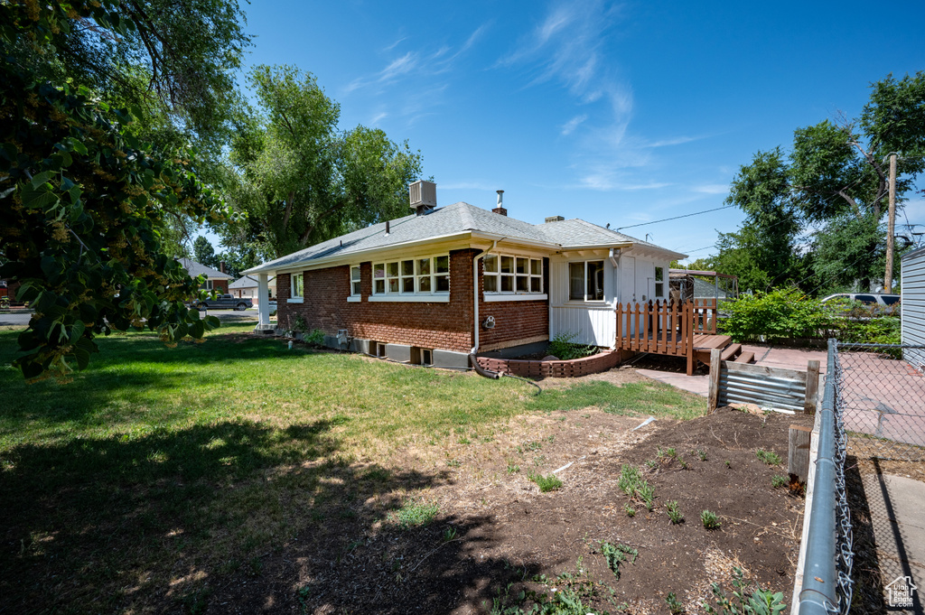 Rear view of house with a wooden deck, brick siding, and a lawn
