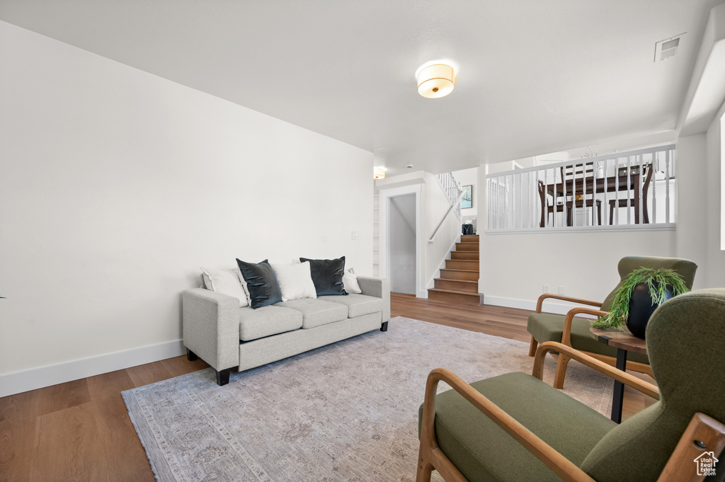 Living area featuring baseboards, stairway, and wood finished floors