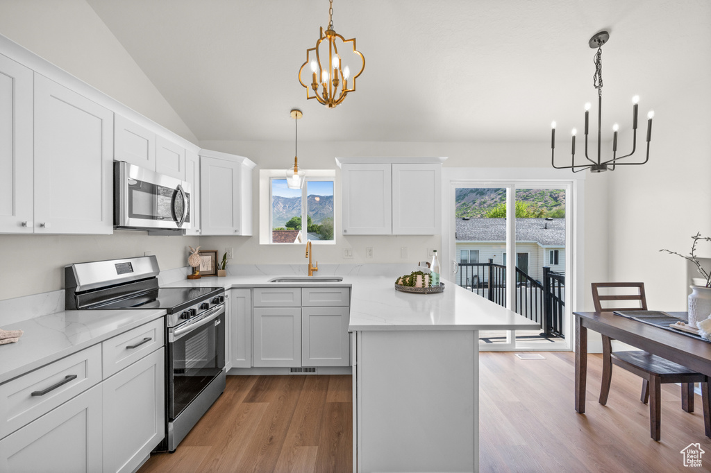 Kitchen with appliances with stainless steel finishes, a chandelier, a sink, light wood-style flooring, and plenty of natural light