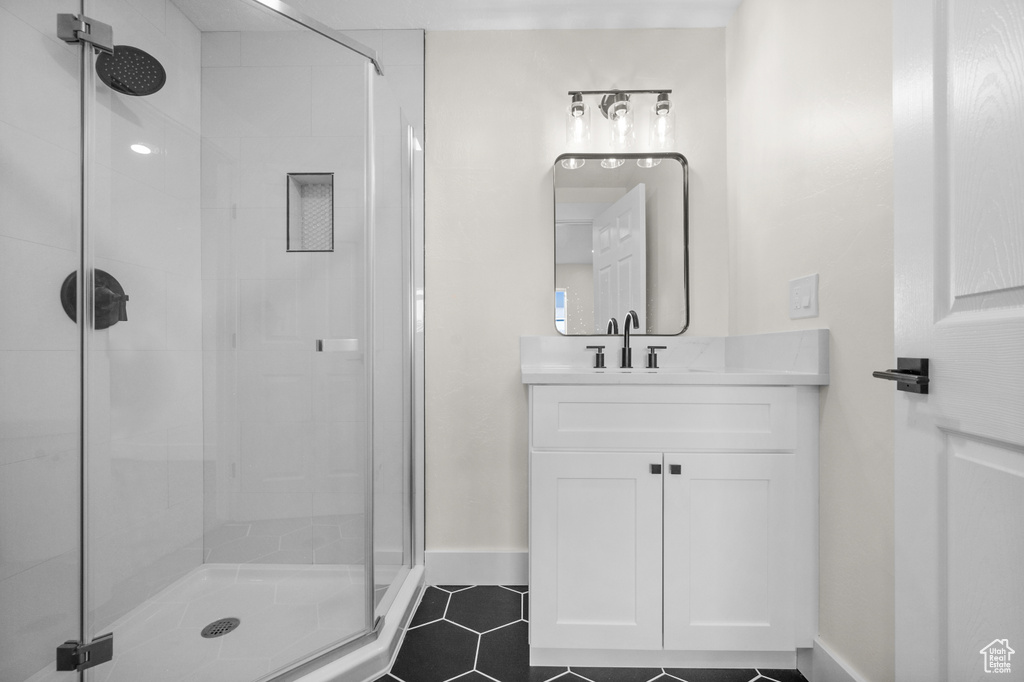 Bathroom featuring a stall shower, vanity, tile patterned floors, and baseboards