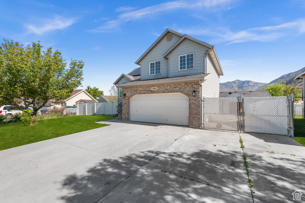 Traditional-style home featuring a gate, driveway, brick siding, and an attached garage