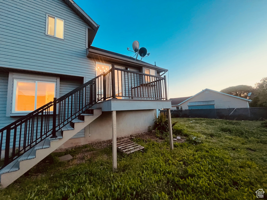Back of property at dusk featuring stairway and a lawn