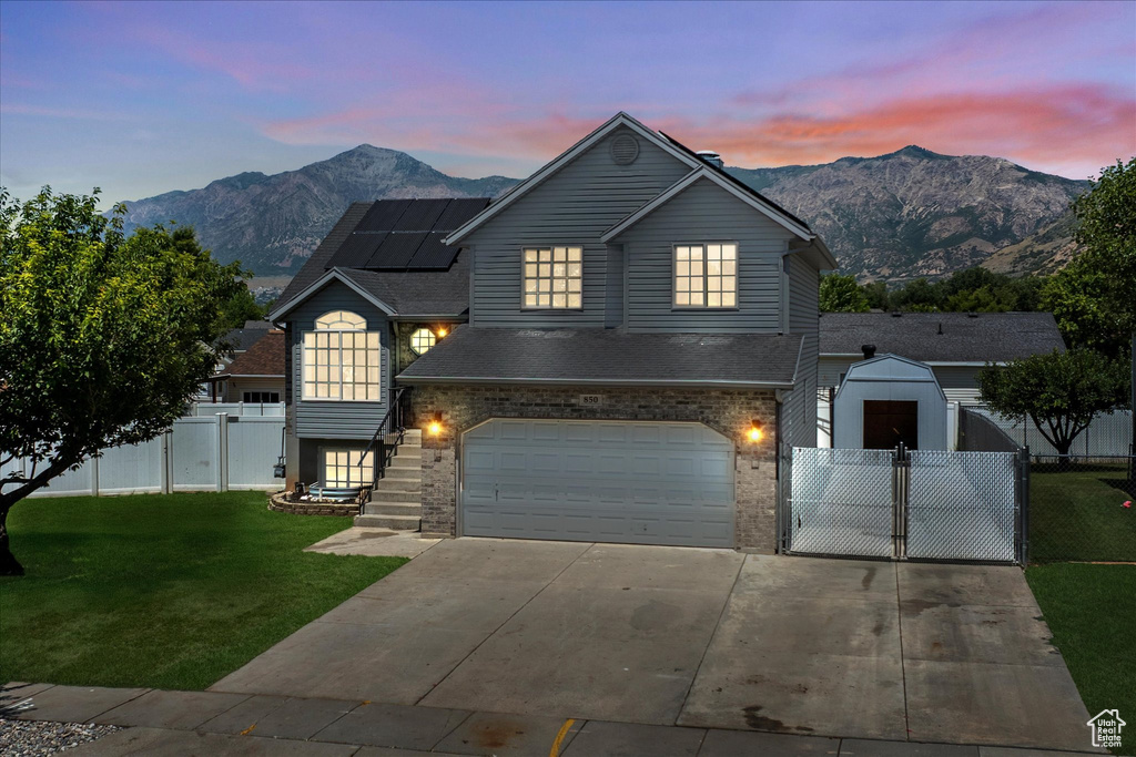 Traditional-style house with a mountain view, solar panels, a garage, driveway, and a gate