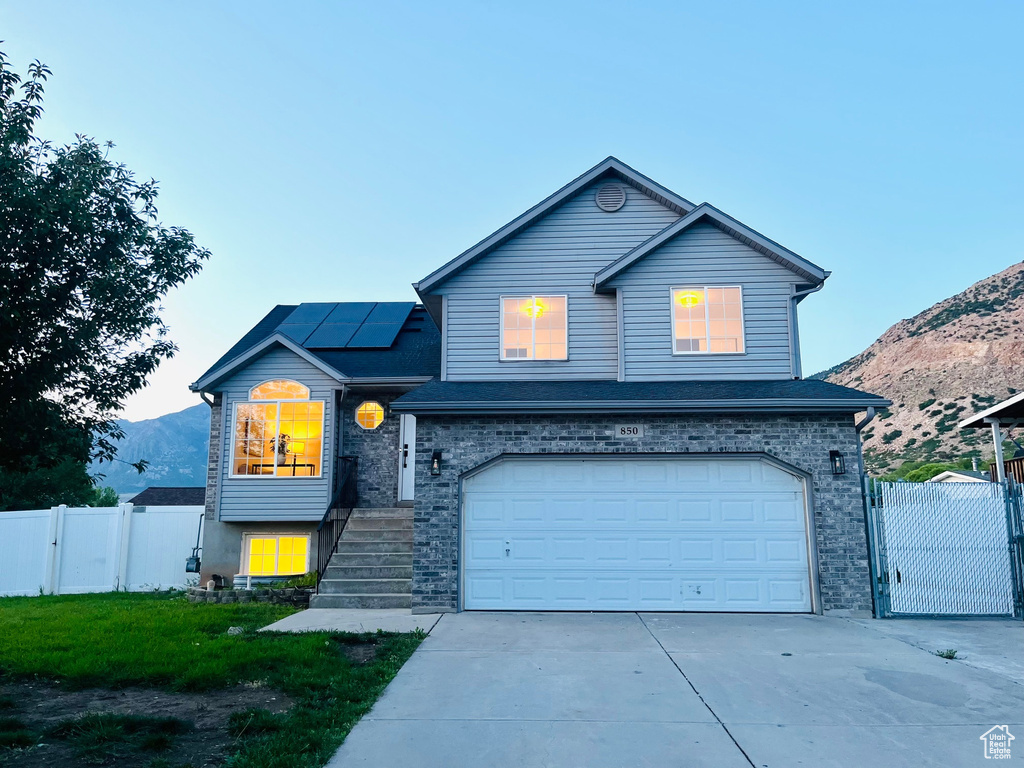 Traditional-style home featuring a gate, solar panels, an attached garage, and a mountain view