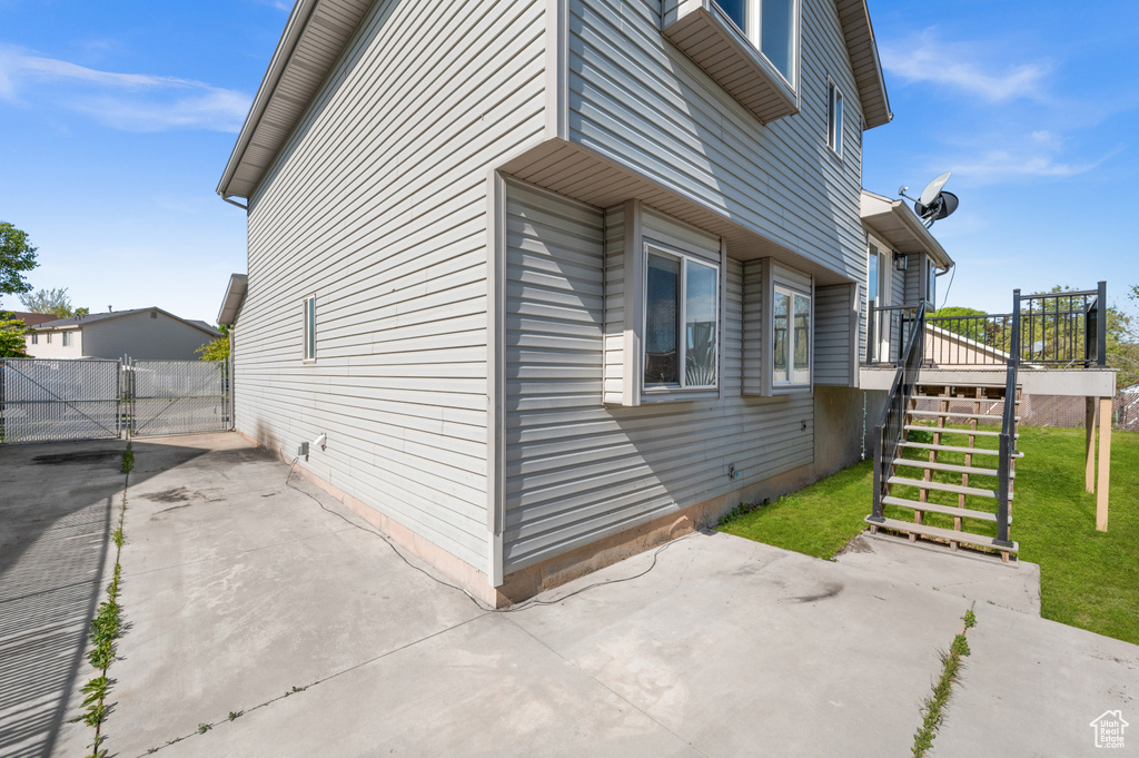 View of home's exterior featuring a patio area, stairs, a wooden deck, and a gate