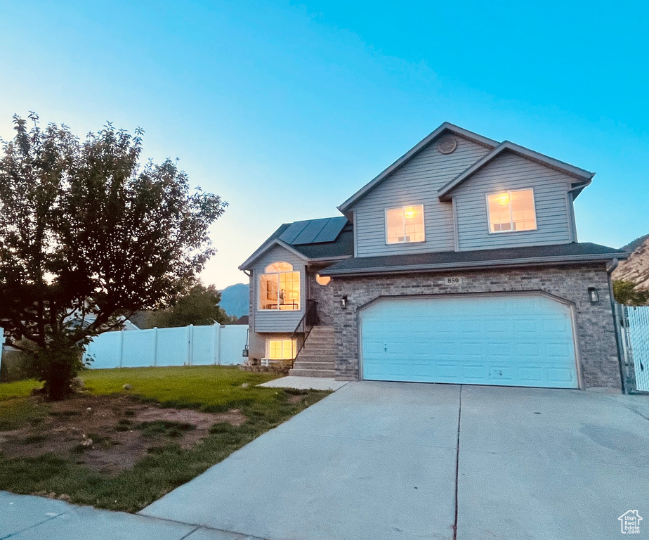 Traditional-style home with solar panels, an attached garage, driveway, and stone siding