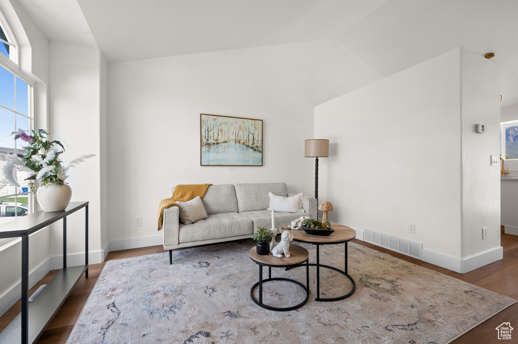 Living area featuring lofted ceiling, wood finished floors, and baseboards