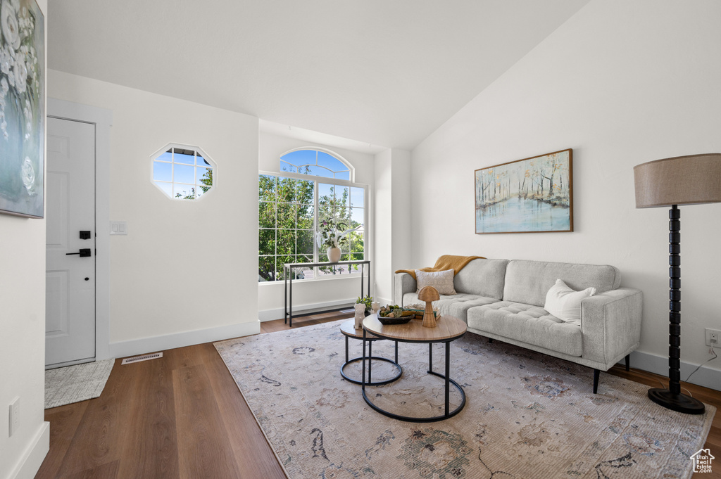 Living area featuring wood finished floors, baseboards, and high vaulted ceiling