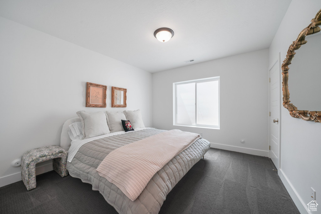 Bedroom with dark colored carpet and baseboards