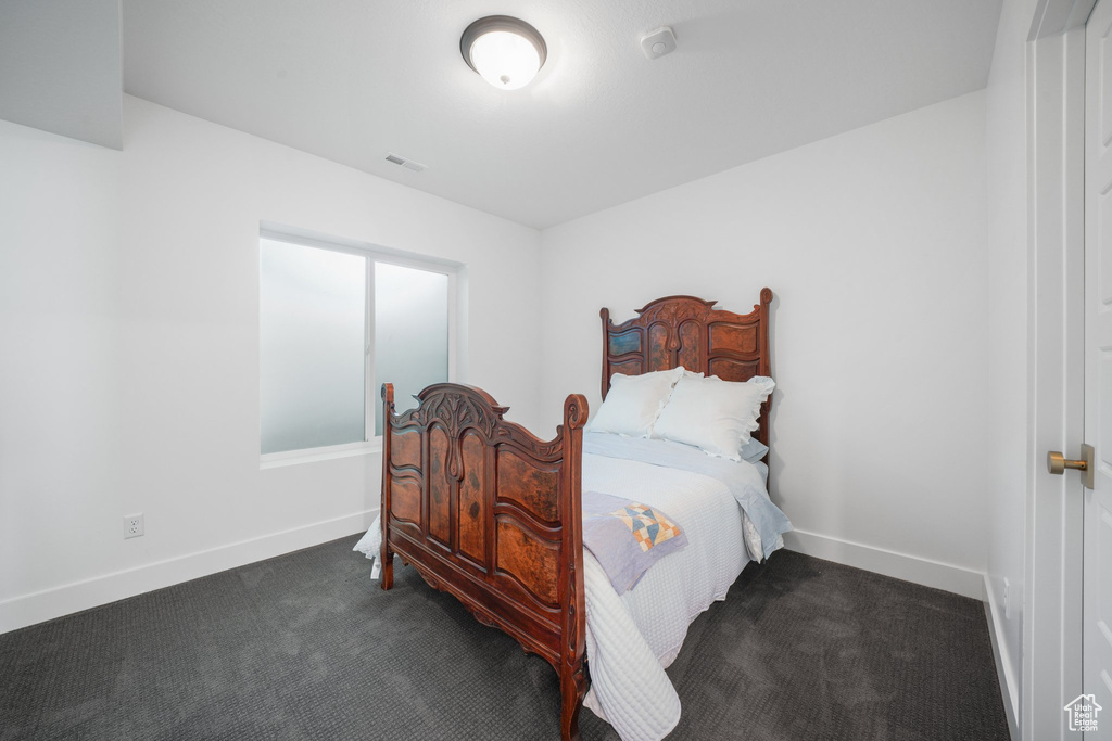 Bedroom with dark carpet and baseboards