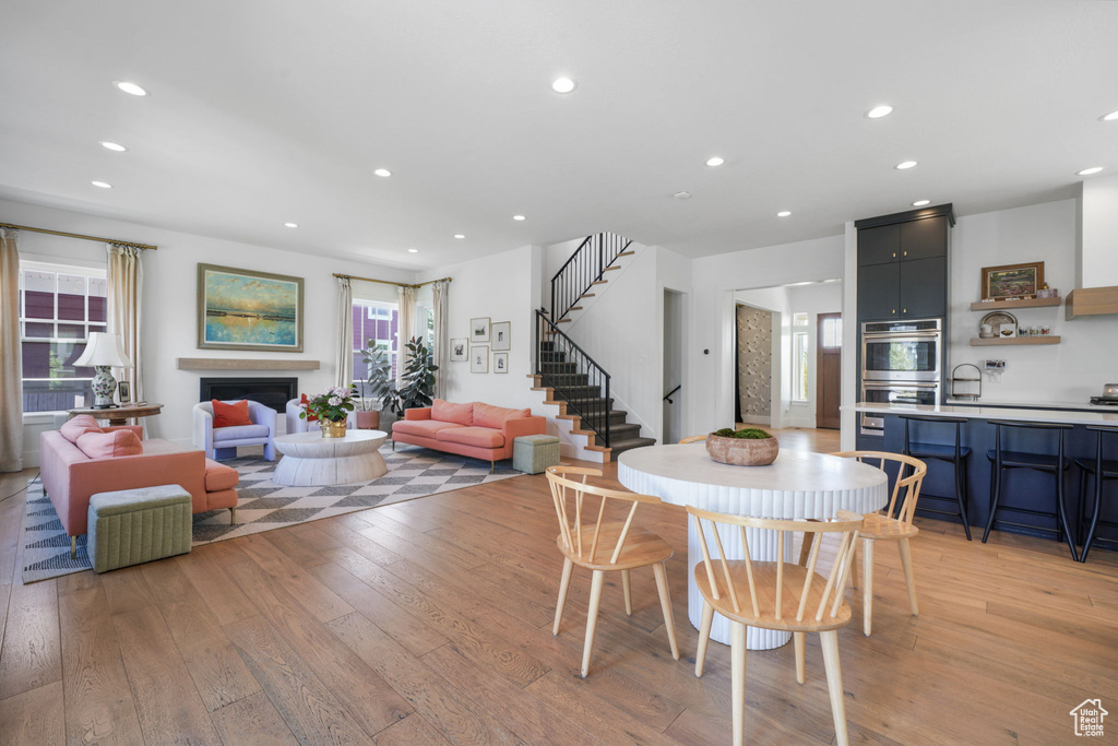 Dining area featuring light wood-style floors, healthy amount of natural light, stairs, recessed lighting, and a fireplace