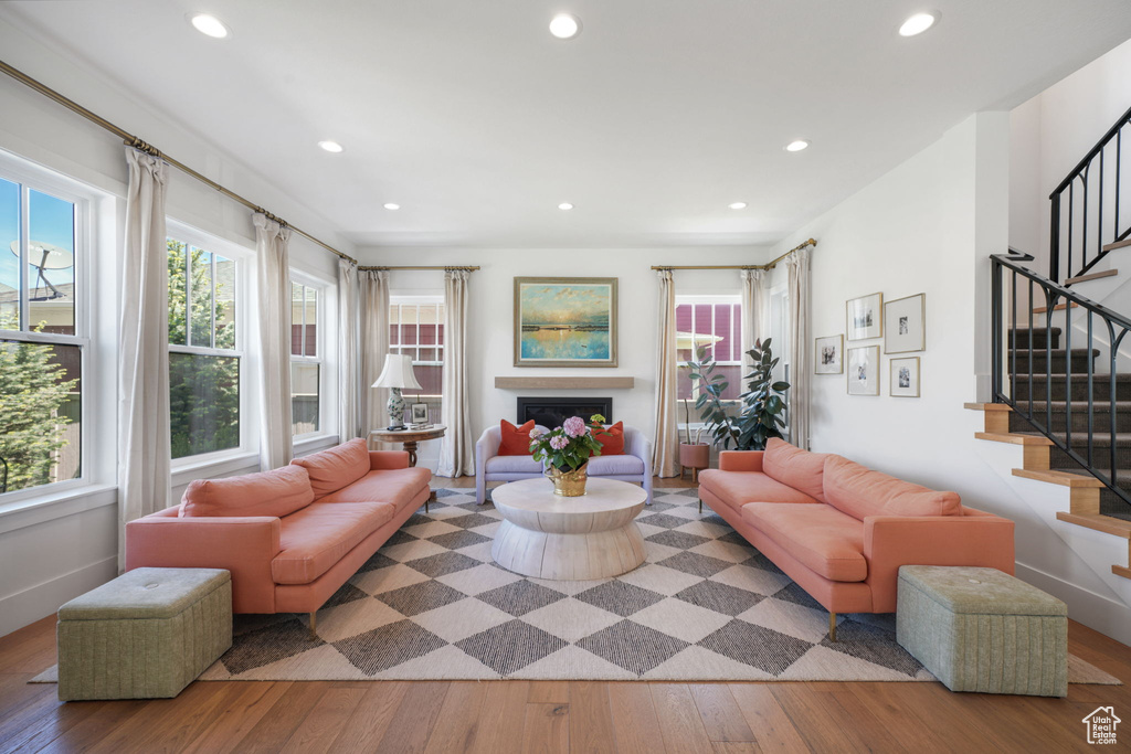 Living room with hardwood / wood-style flooring, healthy amount of natural light, recessed lighting, stairway, and a fireplace