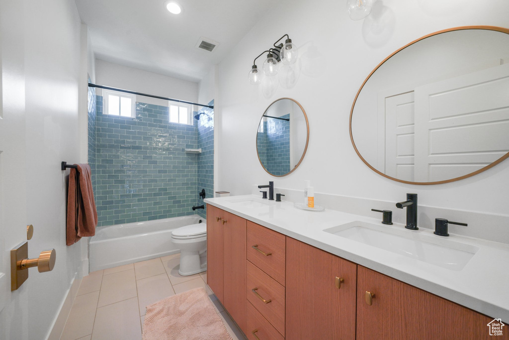 Bathroom with toilet, double vanity, tile patterned floors, bathtub / shower combination, and baseboards