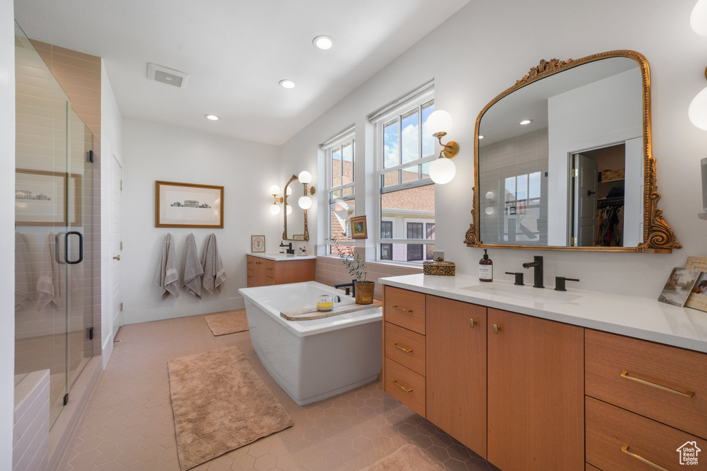 Full bath with a shower stall, recessed lighting, a soaking tub, two vanities, and tile patterned flooring