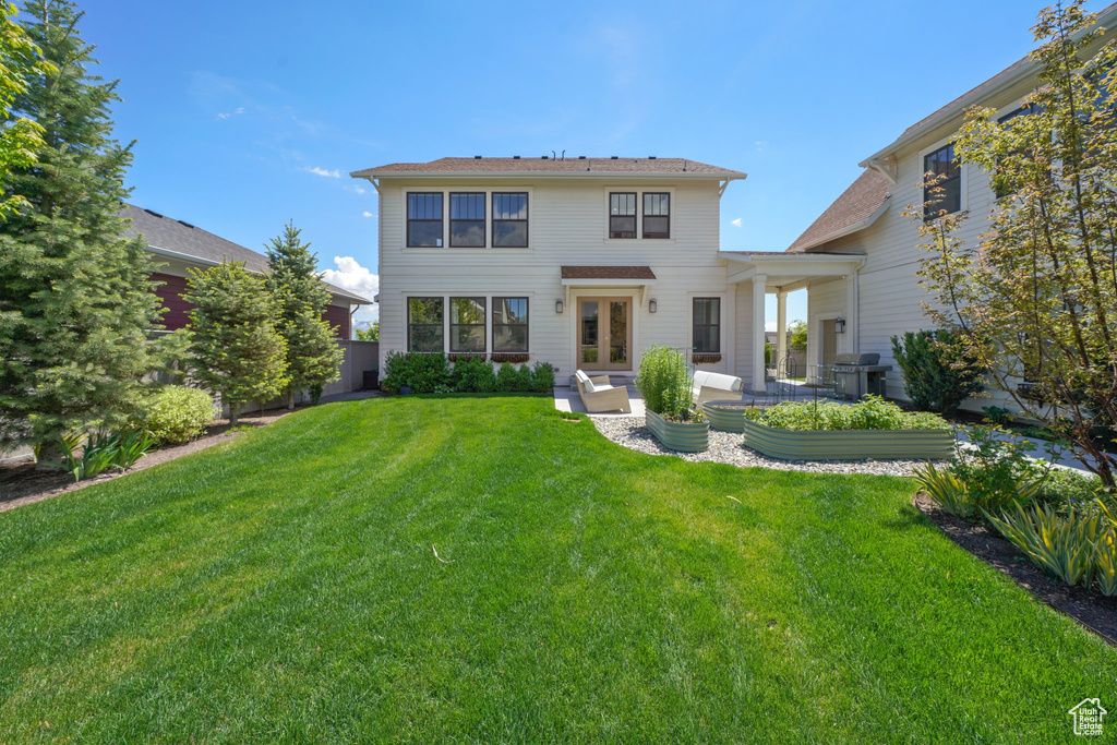 Rear view of property featuring a lawn and a patio area