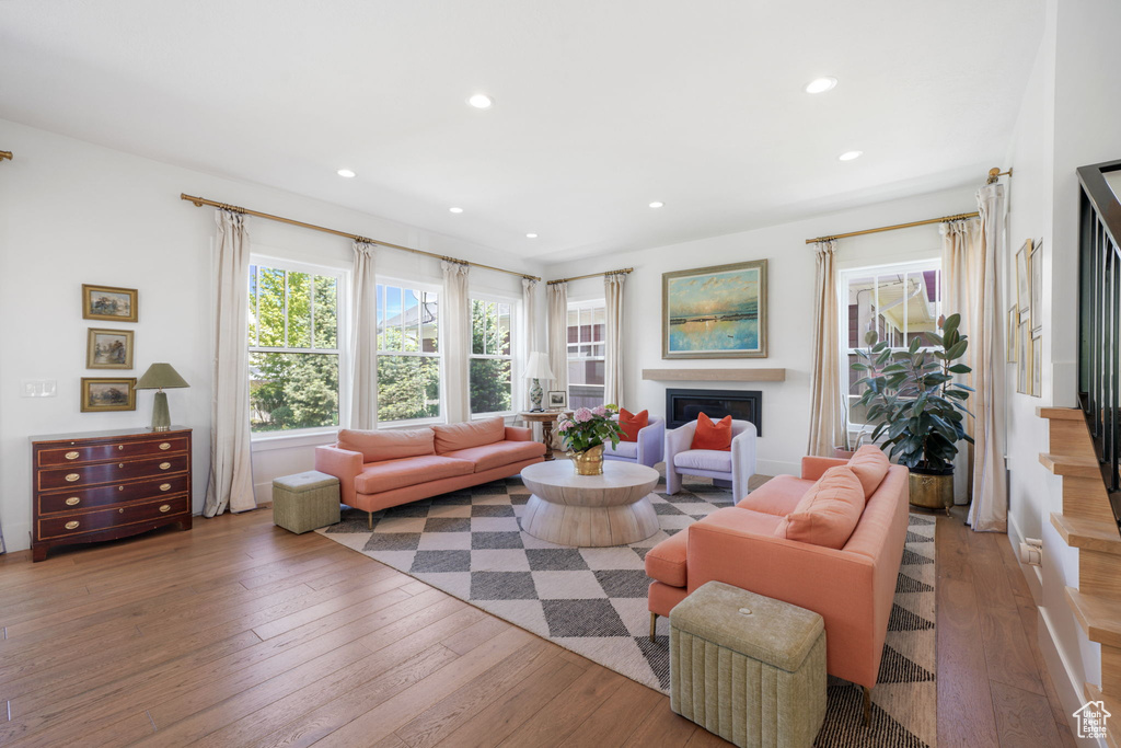 Living room with hardwood / wood-style floors, stairs, recessed lighting, and a glass covered fireplace