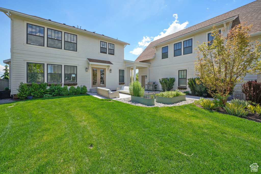 Rear view of house featuring a yard, outdoor lounge area, and french doors
