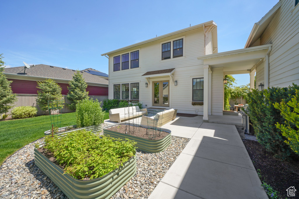 Rear view of property featuring a patio area, a yard, a vegetable garden, french doors, and outdoor lounge area