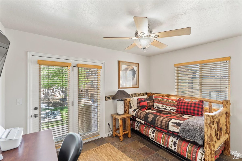 Bedroom featuring stone finish flooring, baseboards, access to exterior, and ceiling fan