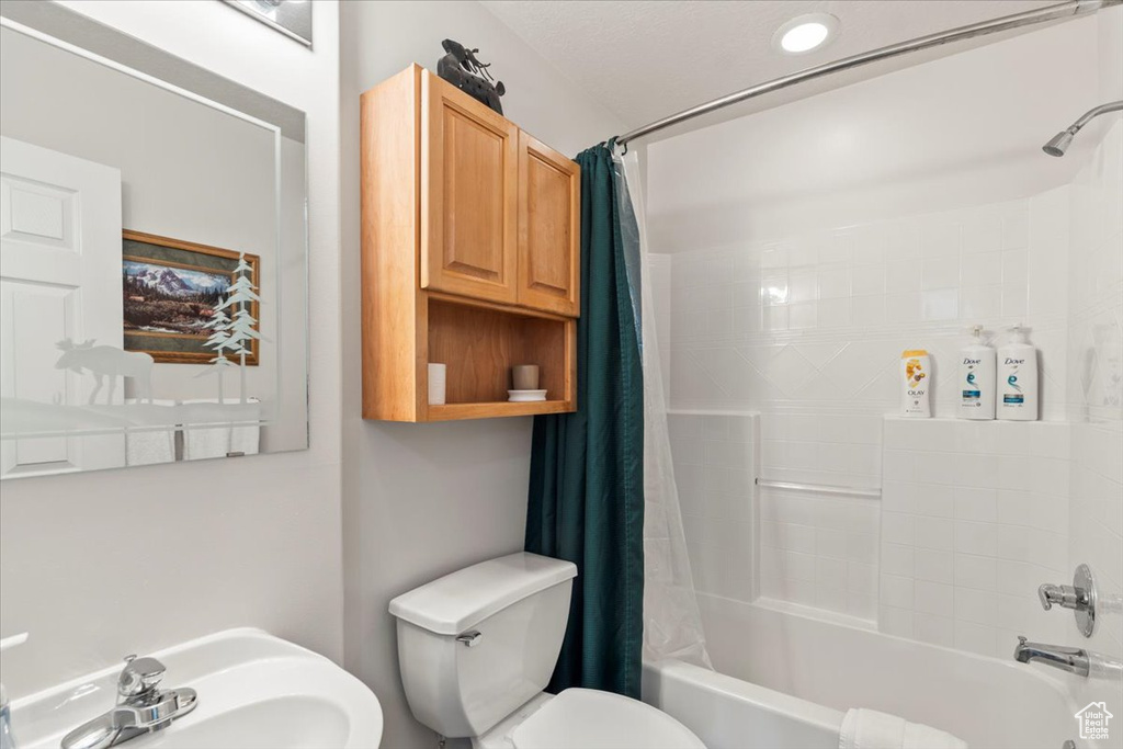 Full bathroom with a sink, toilet, and shower / bathtub combination with curtain