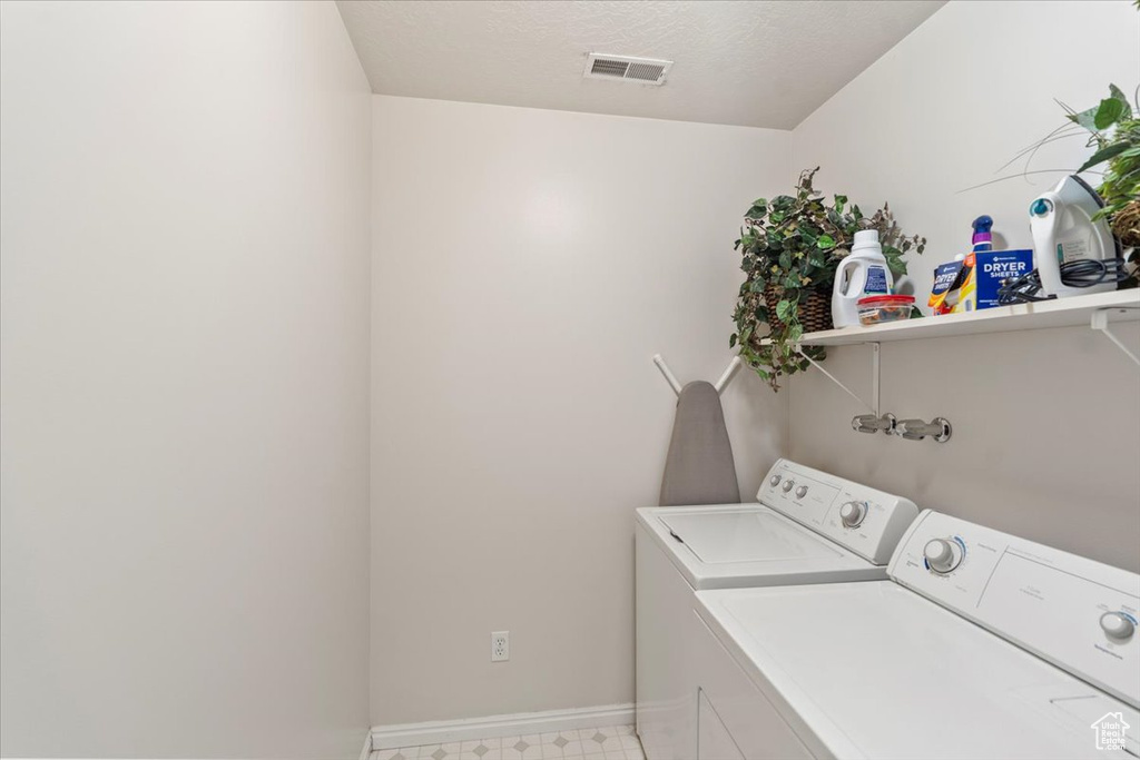 Clothes washing area with baseboards, washing machine and dryer, laundry area, and visible vents