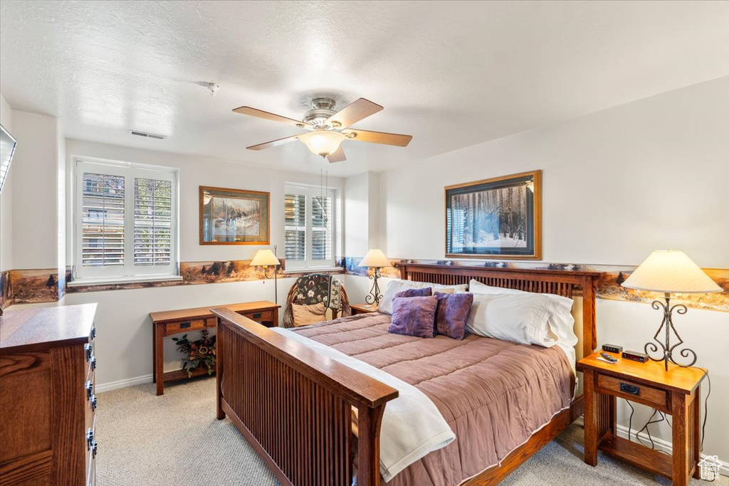 Bedroom featuring light colored carpet, multiple windows, visible vents, and baseboards