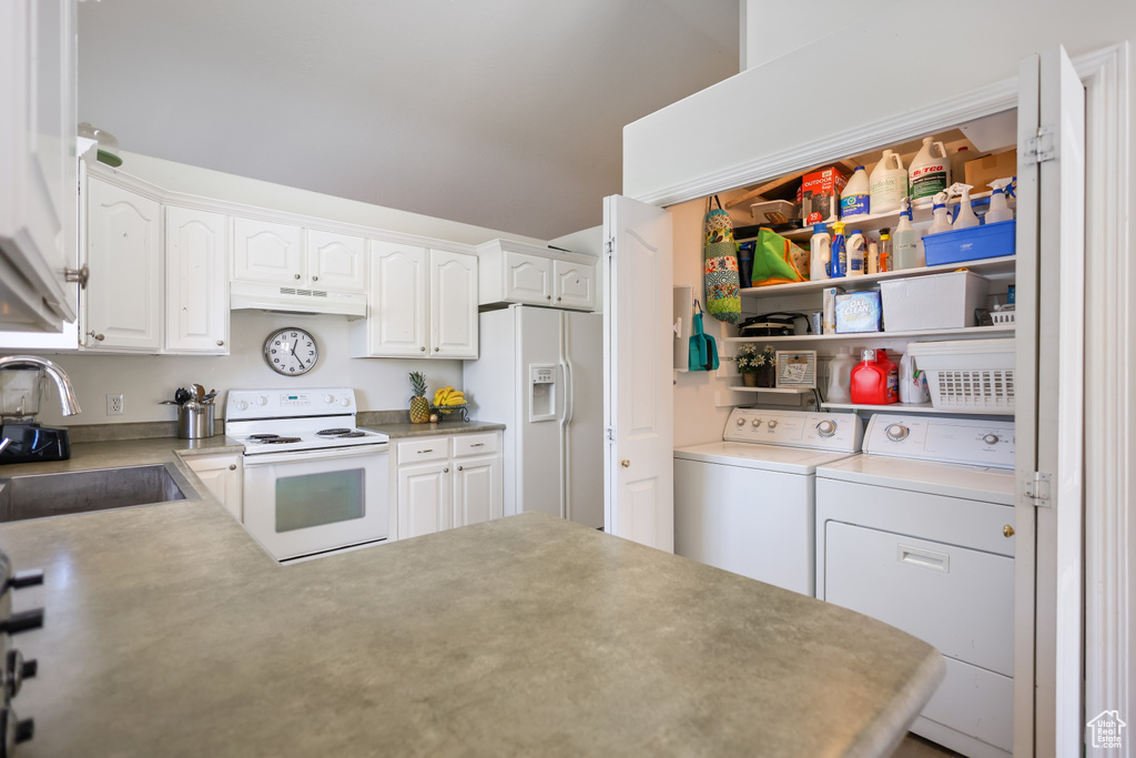Kitchen featuring white appliances, washer and dryer, a sink, white cabinets, and under cabinet range hood