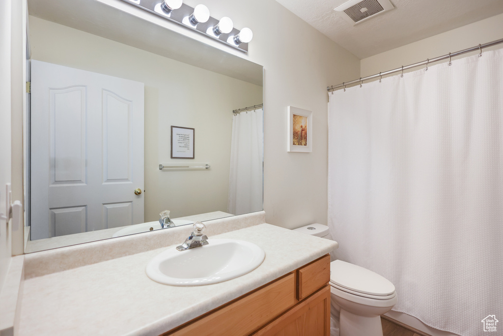 Full bathroom with toilet, vanity, and curtained shower