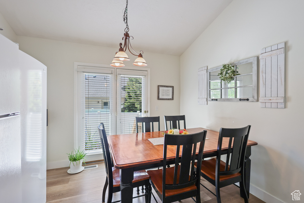 Dining area with baseboards, wood finished floors, and vaulted ceiling