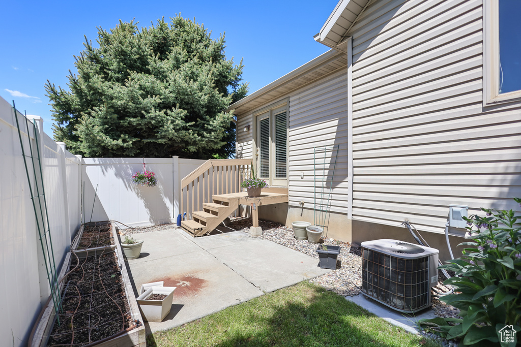 View of patio with cooling unit and a fenced backyard
