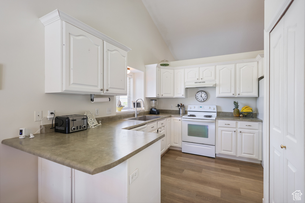 Kitchen with electric range, a peninsula, a sink, white cabinets, and under cabinet range hood