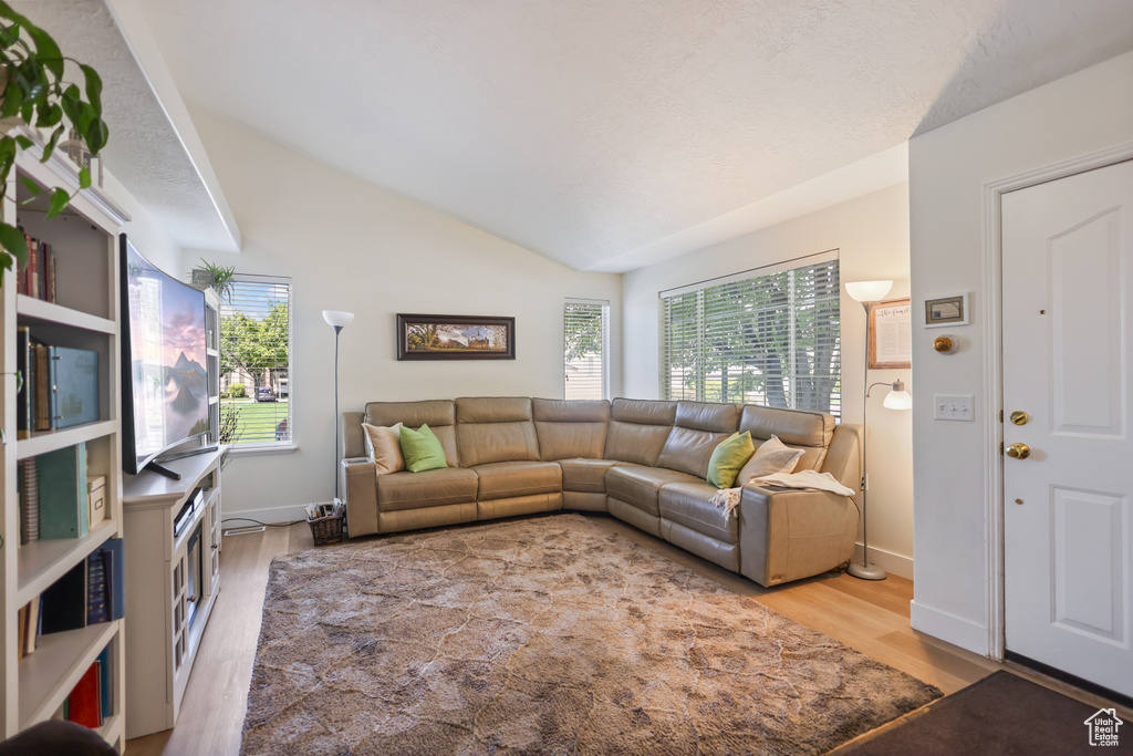 Living area featuring wood finished floors, lofted ceiling, and baseboards