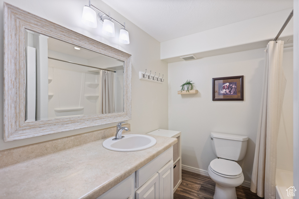 Full bath featuring wood finished floors, toilet, vanity, and curtained shower