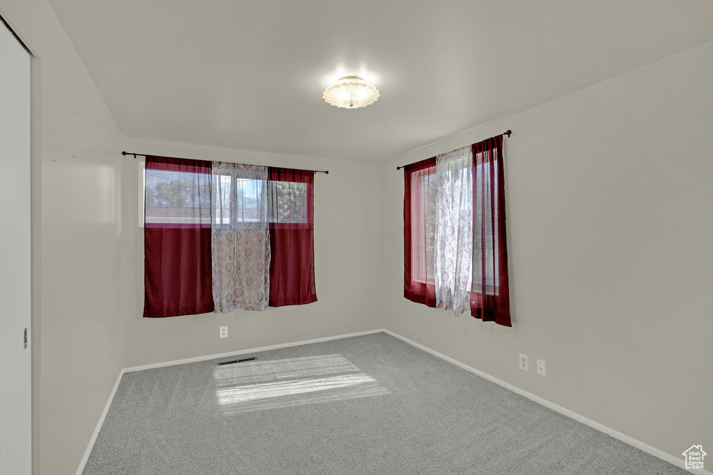 Empty room featuring carpet flooring, baseboards, and healthy amount of natural light