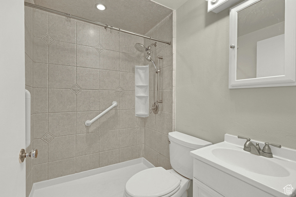 Bathroom featuring toilet, tiled shower, and vanity
