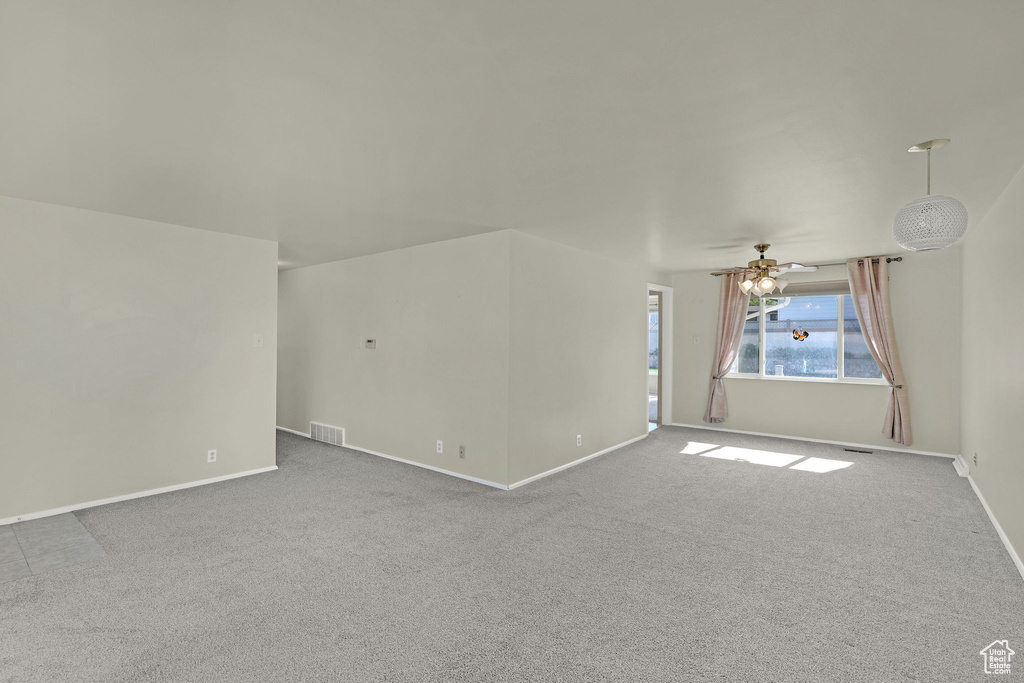Unfurnished living room with carpet, baseboards, and ceiling fan